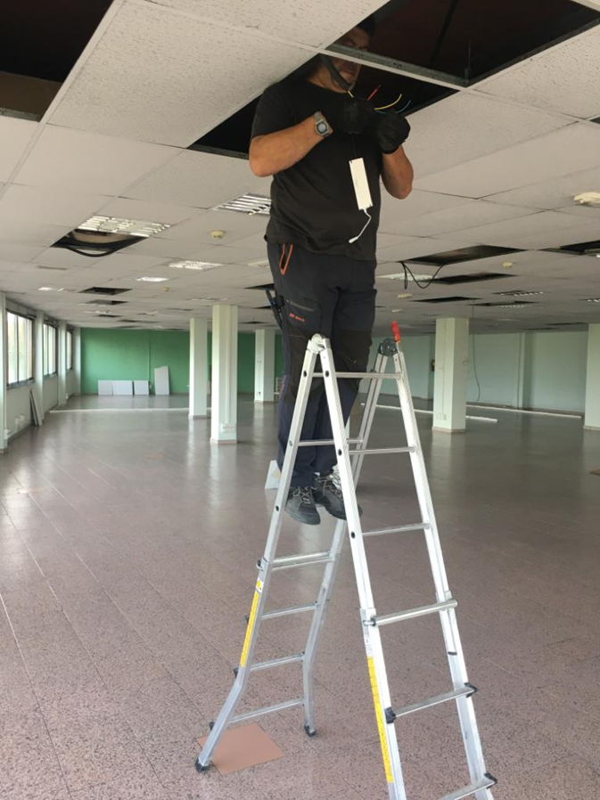 Electricista realizando una instalación y reparación eléctrica de pantallas led-en una oficina de majadahonda